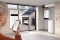 The picture shows a man controlling the Viessmann energy system, including the Vitocharge VX3 electricity storage unit, via a smartphone app. A photovoltaic system and an electric car charging can be seen through a window.
